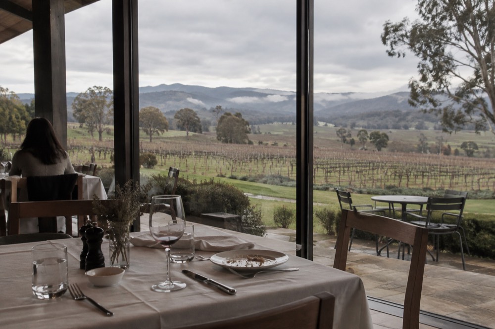Historic stone winery building with bare winter vines and a pale morning sky
