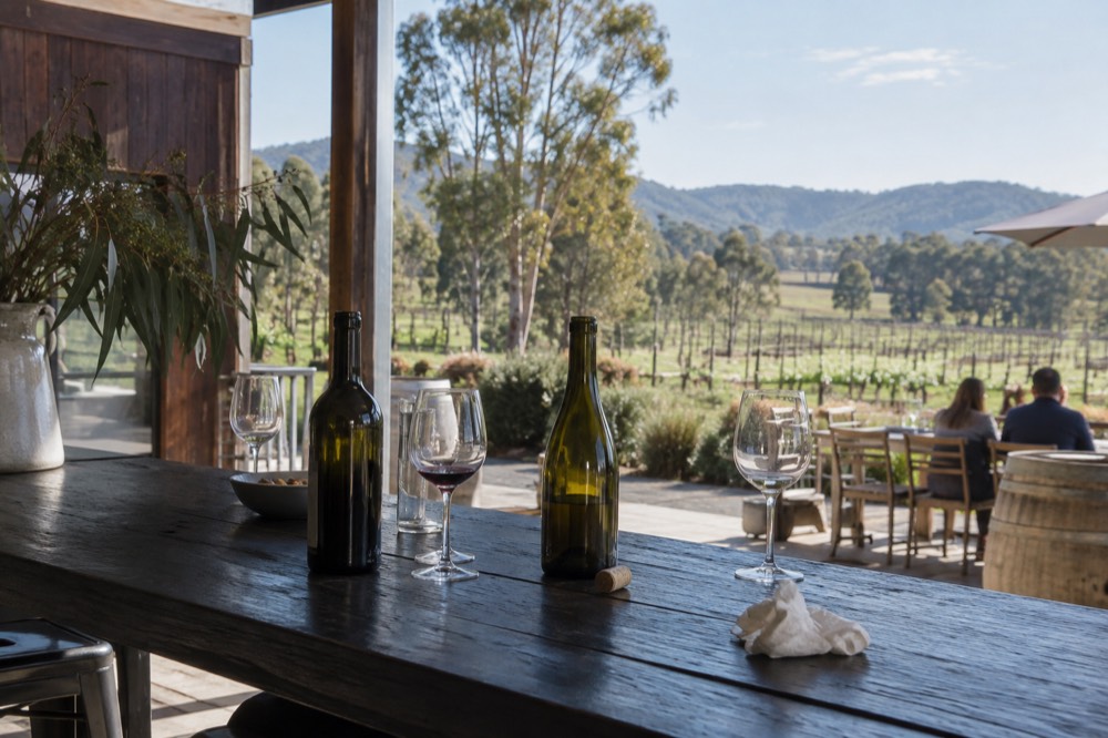 A cellar door tasting bench with wine glasses and open bottles