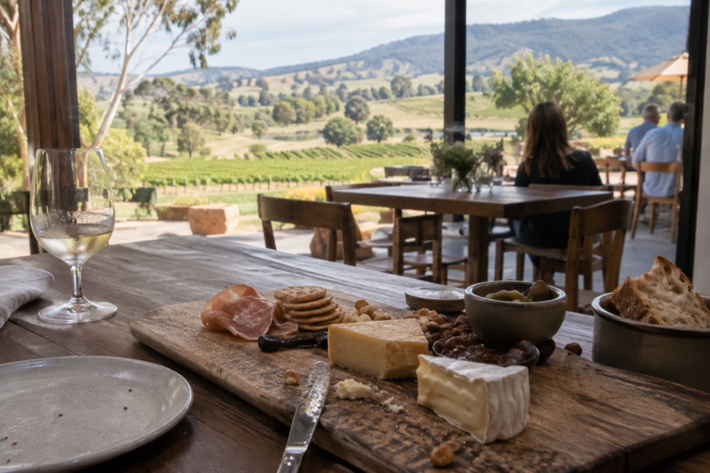 A platter of cheese and charcuterie on a wooden board on a cellar door table