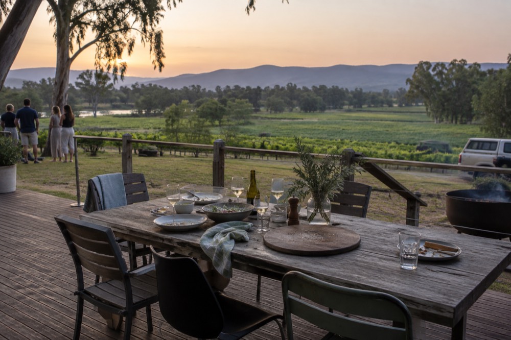 A lunch table set for a small party on a winery terrace overlooking vines