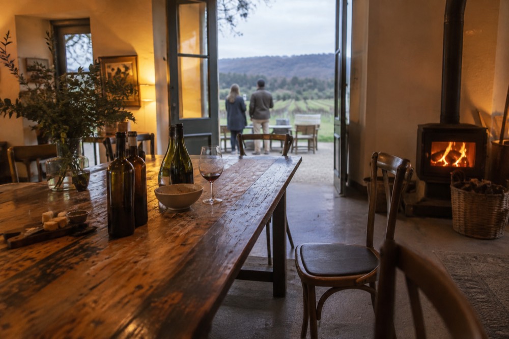 Cellar door tasting bench with glassware and wine bottles in warm indoor light
