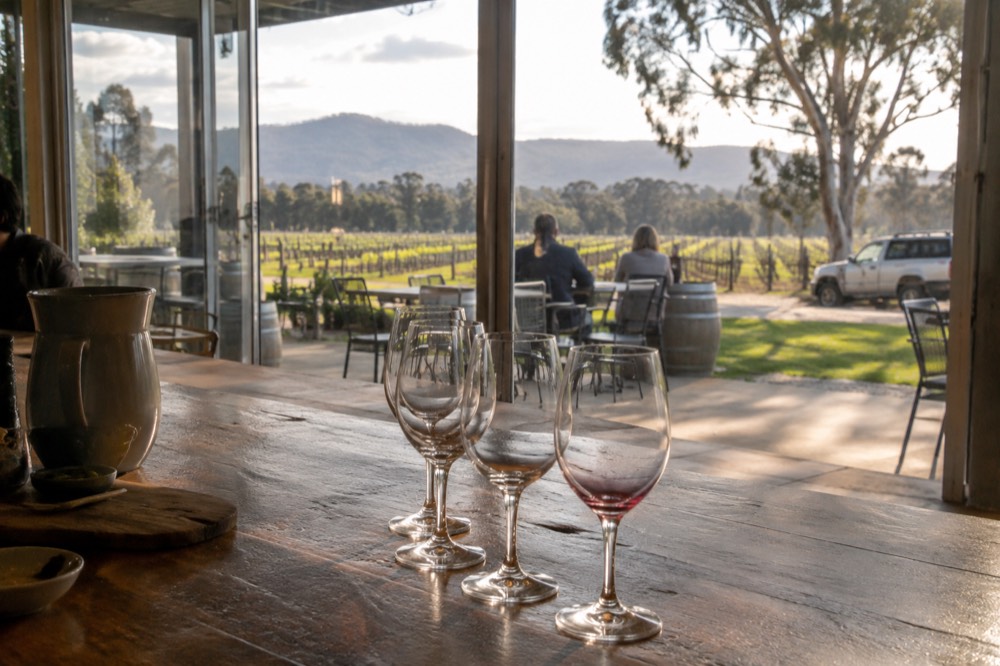 Close view of wine glasses lined on a wooden tasting bench in soft light
