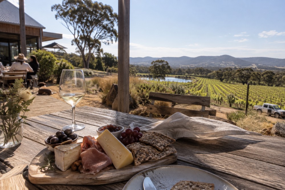 A wooden platter of cheese and charcuterie on a winery table outdoors