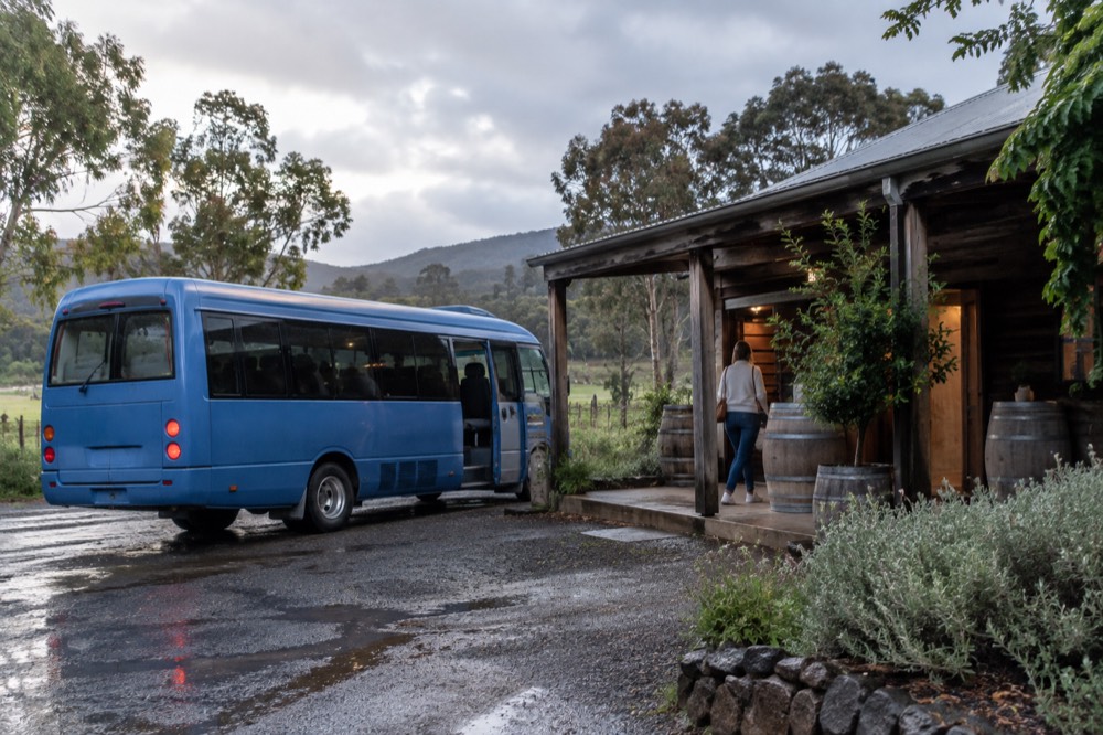 A small shuttle bus parked outside a cellar door entrance