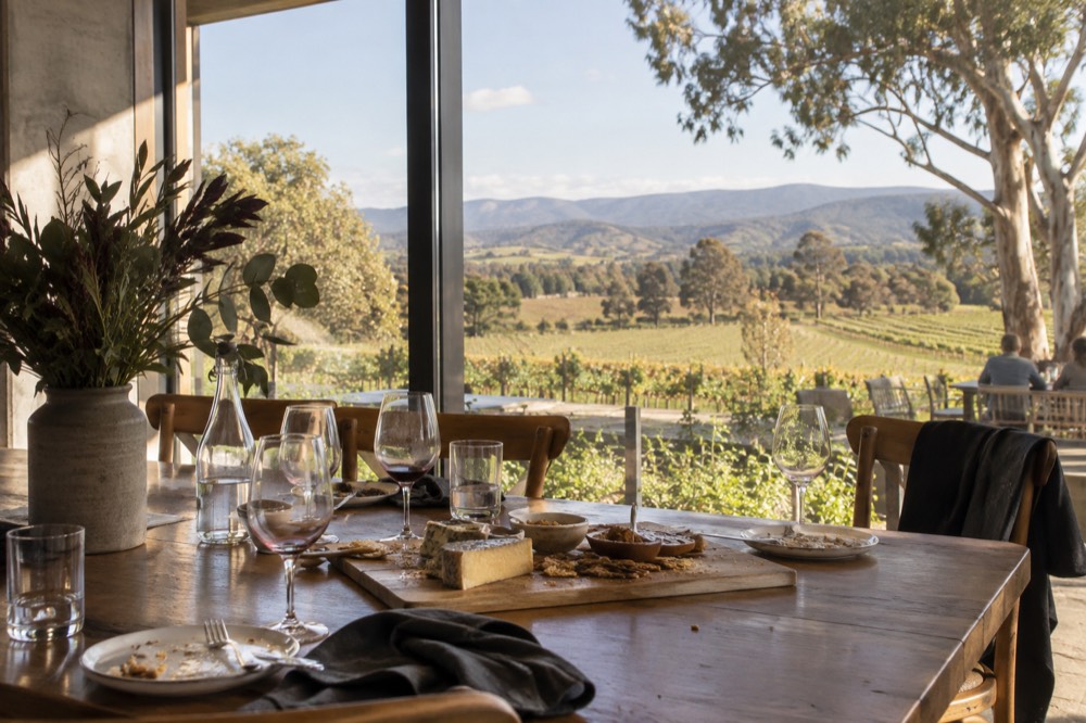 Laid table with wine glasses and a cheese board beside a window overlooking the valley