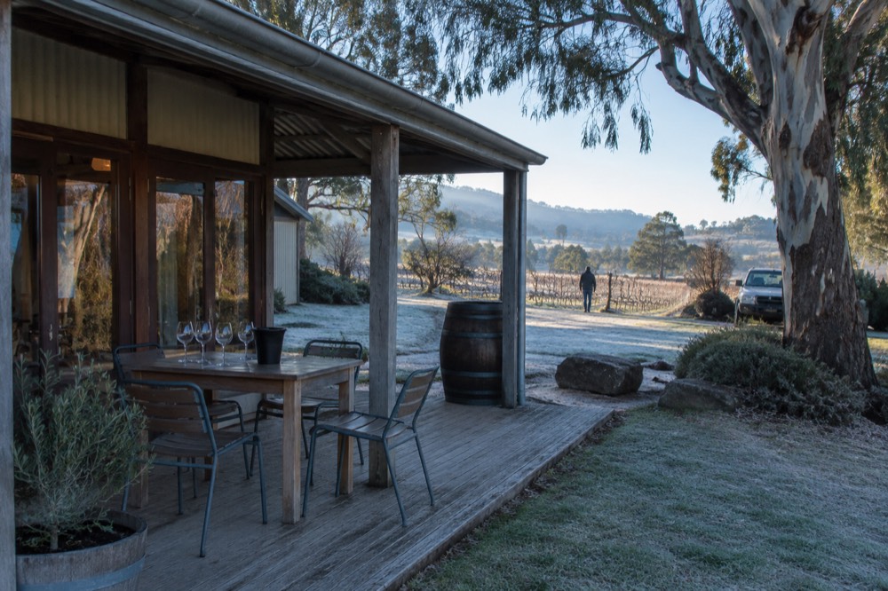 A modest winery door with a single table set for a booked tasting