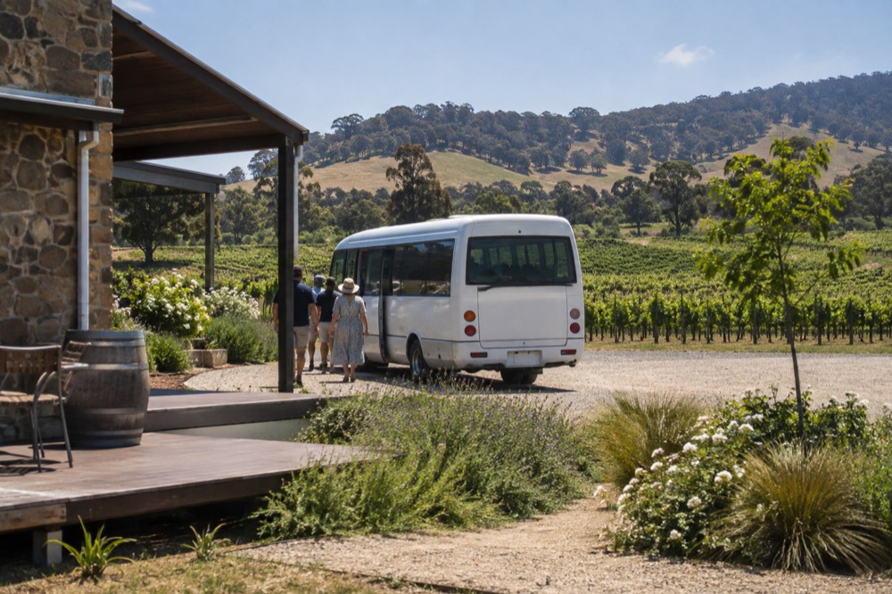 A small bus parked beside a cellar door with passengers boarding
